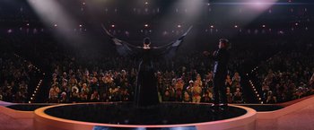 Movie still from “The Hunger Games: Catching Fire” (2013), directed by Francis Lawrence – A woman in a black dress on a stage; Wide shot, Low angle