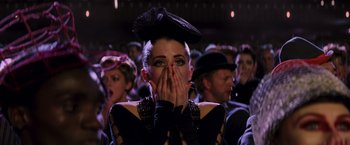 Movie still from “The Hunger Games: Catching Fire” (2013), directed by Francis Lawrence – A woman in a black outfit covering her mouth with her hands; Close Up shot, Low angle