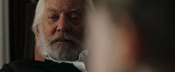 Movie still from “The Hunger Games: Catching Fire” (2013), directed by Francis Lawrence – An older man with a beard and a white shirt; Close Up shot, Over the shoulder angle
