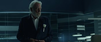 Movie still from “The Hunger Games: Catching Fire” (2013), directed by Francis Lawrence – An older man with a white rose in his lapel; Close Up shot, Over the shoulder angle