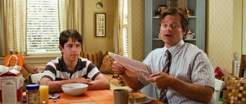 Movie still from “Diary of a Wimpy Kid: Dog Days” (2012), directed by David Bowers – Two people sitting at a table with a newspaper; Medium shot, Over the shoulder angle