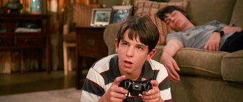 Movie still from “Diary of a Wimpy Kid: Dog Days” (2012), directed by David Bowers – A young man holding a video game controller in a living room; Close Up shot, Over the shoulder angle