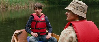 Movie still from “Diary of a Wimpy Kid: Dog Days” (2012), directed by David Bowers – A young boy sitting on a boat next to an older man; Medium shot, Over the shoulder angle