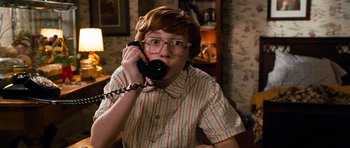 Movie still from “Diary of a Wimpy Kid: Dog Days” (2012), directed by David Bowers – A person sitting at a table talking on a phone; Medium shot, High angle