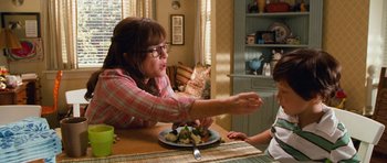 Movie still from “Diary of a Wimpy Kid: Dog Days” (2012), directed by David Bowers – A woman sitting at a table with a plate of food; Medium shot, Over the shoulder angle