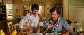 Movie still from “Diary of a Wimpy Kid: Dog Days” (2012), directed by David Bowers – Two men are sitting at a table and one of them is holding a magnifying glass; Medium shot, Over the shoulder angle