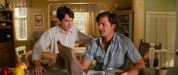 Movie still from “Diary of a Wimpy Kid: Dog Days” (2012), directed by David Bowers – A man and a young boy are looking at a newspaper; Medium shot, Over the shoulder angle