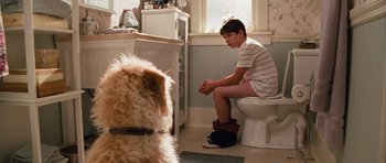 Movie still from “Diary of a Wimpy Kid: Dog Days” (2012), directed by David Bowers – A boy sitting on a toilet in a bathroom next to a dog; Medium shot, Over the shoulder angle