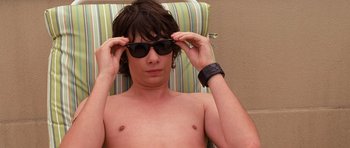 Movie still from “Diary of a Wimpy Kid: Dog Days” (2012), directed by David Bowers – A shirtless man wearing sunglasses while sitting in a chair; Close Up shot, High angle