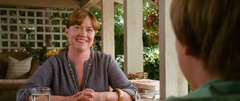 Movie still from “Diary of a Wimpy Kid: Dog Days” (2012), directed by David Bowers – A woman sitting at an outdoor table smiling for the camera; Medium shot, Over the shoulder angle