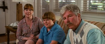 Movie still from “Diary of a Wimpy Kid: Dog Days” (2012), directed by David Bowers – Three people sitting on a couch looking at the camera; Medium shot, Over the shoulder angle