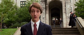 Movie still from “Diary of a Wimpy Kid: Dog Days” (2012), directed by David Bowers – A young man in a suit and tie standing in front of a building; Close Up shot, Over the shoulder angle