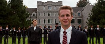 Movie still from “Diary of a Wimpy Kid: Dog Days” (2012), directed by David Bowers – A man in a suit and tie standing in front of a building; Medium shot, Low angle