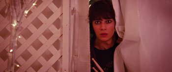 Movie still from “Diary of a Wimpy Kid: Dog Days” (2012), directed by David Bowers – A woman is peeking through a window with a pair of drumsticks in front of her face; Medium shot, Low angle