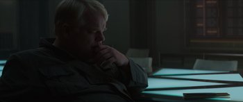 Movie still from “The Hunger Games: Mockingjay - Part 1” (2014), directed by Francis Lawrence – A man sitting at a table with his hand on his chin; Close Up shot, Over the shoulder angle