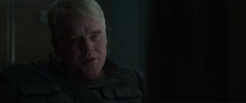 Movie still from “The Hunger Games: Mockingjay - Part 1” (2014), directed by Francis Lawrence – A person wearing a suit and tie; Close Up shot, Over the shoulder angle