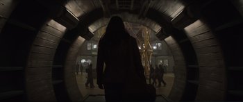 Movie still from “The Hunger Games: Mockingjay - Part 1” (2014), directed by Francis Lawrence – A woman is walking through a tunnel in the dark; Wide shot, Over the shoulder angle