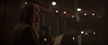 Movie still from “The Hunger Games: Mockingjay - Part 1” (2014), directed by Francis Lawrence – A woman is speaking at a microphone in front of an audience; Close Up shot, Low angle