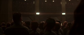 Movie still from “The Hunger Games: Mockingjay - Part 1” (2014), directed by Francis Lawrence – A group of people sitting in front of an audience; Wide shot, Low angle