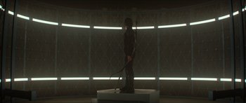 Movie still from “The Hunger Games: Mockingjay - Part 1” (2014), directed by Francis Lawrence – A person standing in a room holding a whip; Wide shot, Low angle