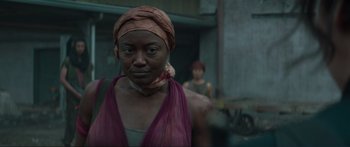 Movie still from “The Hunger Games: Mockingjay - Part 1” (2014), directed by Francis Lawrence – A woman in a purple shirt and a red head scarf; Close Up shot, Over the shoulder angle