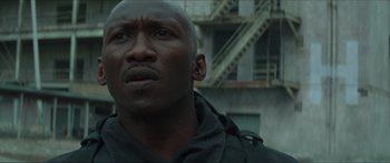 Movie still from “The Hunger Games: Mockingjay - Part 1” (2014), directed by Francis Lawrence – A person with a building in the background; Close Up shot, Low angle