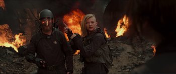 Movie still from “The Hunger Games: Mockingjay - Part 1” (2014), directed by Francis Lawrence – A woman holding a knife standing in front of a fire; Medium shot, Over the shoulder angle