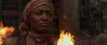 Movie still from “The Hunger Games: Mockingjay - Part 1” (2014), directed by Francis Lawrence – A woman with a head scarf standing in front of a fire; Close Up shot, Over the shoulder angle