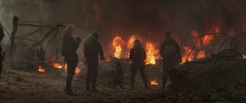 Movie still from “The Hunger Games: Mockingjay - Part 1” (2014), directed by Francis Lawrence – A group of people standing in front of a fire; Wide shot, Low angle