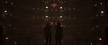 Movie still from “The Hunger Games: Mockingjay - Part 1” (2014), directed by Francis Lawrence – Two women standing in front of an audience in an auditorium; Extreme Wide shot, Overhead angle