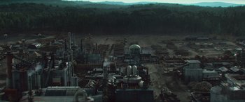 Movie still from “The Hunger Games: Mockingjay - Part 1” (2014), directed by Francis Lawrence – An aerial view of an industrial area with trees in the background; Extreme Wide shot, High angle