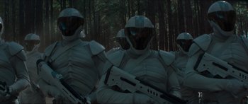 Movie still from “The Hunger Games: Mockingjay - Part 1” (2014), directed by Francis Lawrence – A couple of men in white suits are holding guns; Medium shot, Low angle