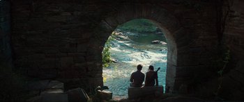 Movie still from “The Hunger Games: Mockingjay - Part 1” (2014), directed by Francis Lawrence – Two people sitting on a bench looking out at a river; Wide shot, High angle