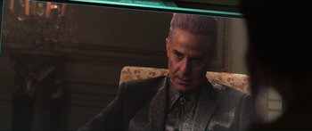 Movie still from “The Hunger Games: Mockingjay - Part 1” (2014), directed by Francis Lawrence – A man sitting in a chair looking at the camera; Close Up shot, Over the shoulder angle