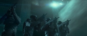 Movie still from “The Hunger Games: Mockingjay - Part 1” (2014), directed by Francis Lawrence – A group of people with guns in a dark room; Wide shot, Low angle