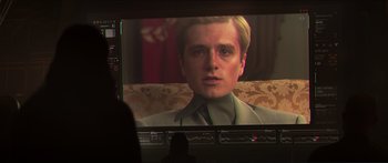 Movie still from “The Hunger Games: Mockingjay - Part 1” (2014), directed by Francis Lawrence – A man is sitting in front of a television screen; Close Up shot, Over the shoulder angle