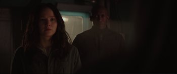 Movie still from “The Hunger Games: Mockingjay - Part 1” (2014), directed by Francis Lawrence – A man and a woman standing next to each other in front of a window; Close Up shot, Over the shoulder angle