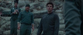 Movie still from “The Hunger Games: Mockingjay - Part 1” (2014), directed by Francis Lawrence – Two men standing next to each other near some rocks; Medium shot, Low angle