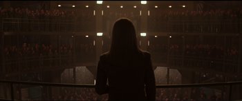 Movie still from “The Hunger Games: Mockingjay - Part 1” (2014), directed by Francis Lawrence – A woman standing in front of an audience in front of a balcony; Extreme Wide shot, Low angle