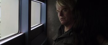 Movie still from “The Hunger Games: Mockingjay - Part 2” (2015), directed by Francis Lawrence – A man with blonde hair looking out a window; Close Up shot, Over the shoulder angle