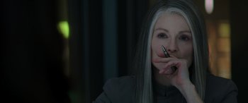 Movie still from “The Hunger Games: Mockingjay - Part 2” (2015), directed by Francis Lawrence – A woman with long white hair is holding a cell phone up to her mouth; Close Up shot, Over the shoulder angle