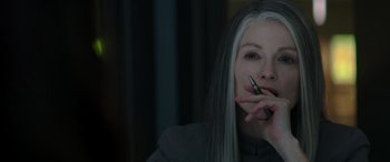 Movie still from “The Hunger Games: Mockingjay - Part 2” (2015), directed by Francis Lawrence – A woman with long white hair is holding a cell phone; Close Up shot, Over the shoulder angle