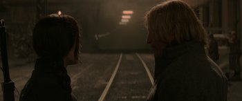 Movie still from “The Hunger Games: Mockingjay - Part 2” (2015), directed by Francis Lawrence – Two people standing next to each other on train tracks; Close Up shot, Over the shoulder angle