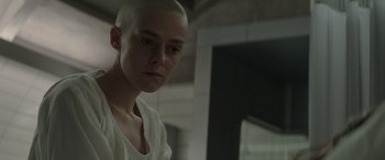 Movie still from “The Hunger Games: Mockingjay - Part 2” (2015), directed by Francis Lawrence – A woman with a shaved head is looking at the camera; Close Up shot, Over the shoulder angle
