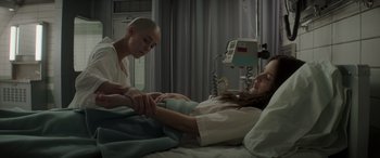 Movie still from “The Hunger Games: Mockingjay - Part 2” (2015), directed by Francis Lawrence – A woman is in a hospital bed with another woman; Medium shot, Over the shoulder angle