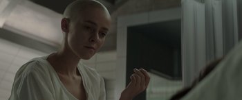 Movie still from “The Hunger Games: Mockingjay - Part 2” (2015), directed by Francis Lawrence – A woman with a shaved head looking at the camera; Close Up shot, Low angle