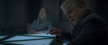 Movie still from “The Hunger Games: Mockingjay - Part 2” (2015), directed by Francis Lawrence – A man and a woman sitting at a table with pens in their hands; Close Up shot, Over the shoulder angle