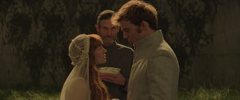 Movie still from “The Hunger Games: Mockingjay - Part 2” (2015), directed by Francis Lawrence – A man and a woman standing next to each other in front of another man; Medium shot, Over the shoulder angle