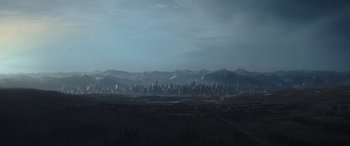 Movie still from “The Hunger Games: Mockingjay - Part 2” (2015), directed by Francis Lawrence – A view of a large city with mountains in the background; Extreme Wide shot, High angle