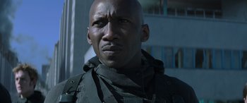 Movie still from “The Hunger Games: Mockingjay - Part 2” (2015), directed by Francis Lawrence – A man with a black shirt on looking at the camera; Close Up shot, Low angle